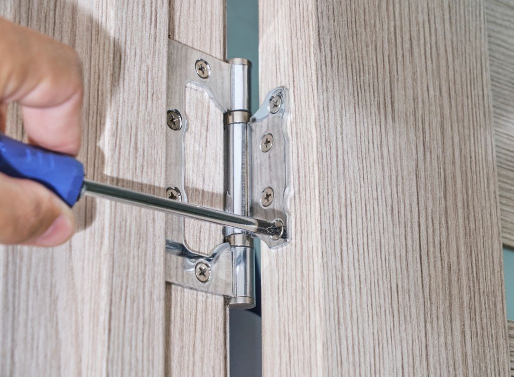 Close-up view of newly installed door jamb corner piece being secured with wood screws