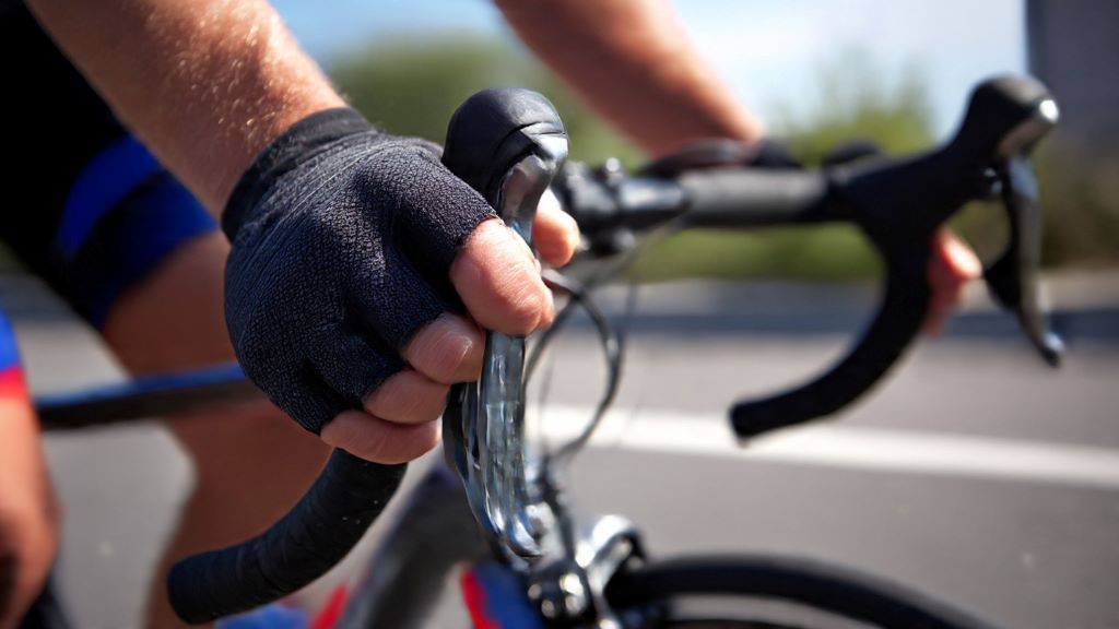 1. Cyclist's hands gripping road bike brake hoods showing proper positioning to prevent numbness and tingling